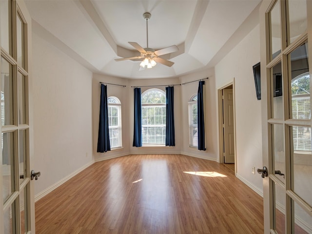 spare room with light hardwood / wood-style floors, french doors, ceiling fan, and a raised ceiling