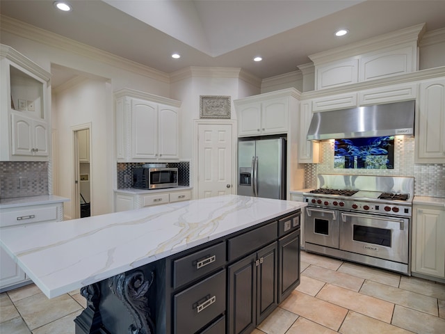 kitchen with white cabinets, tasteful backsplash, a kitchen island, appliances with stainless steel finishes, and extractor fan