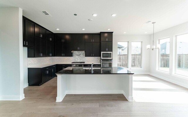 kitchen featuring white cabinetry, appliances with stainless steel finishes, light wood-type flooring, and hanging light fixtures