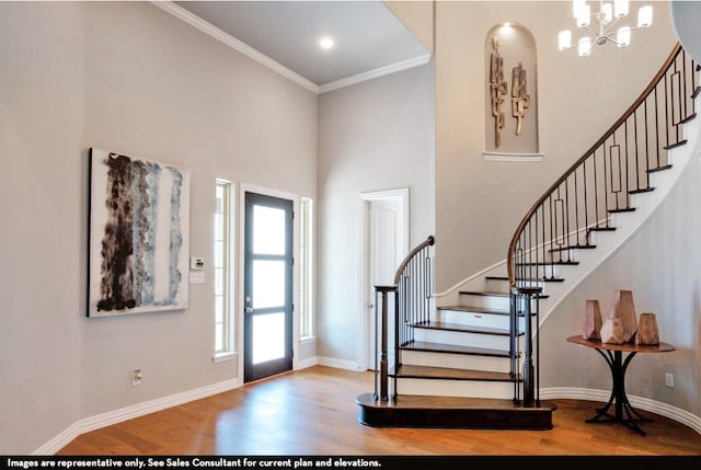 foyer with a chandelier, hardwood / wood-style floors, crown molding, and a high ceiling