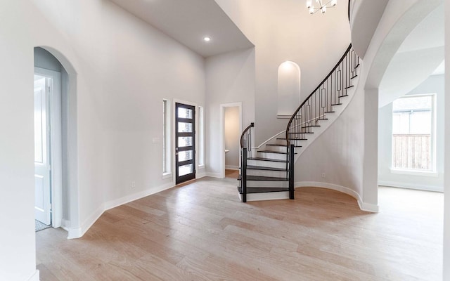 foyer entrance with recessed lighting, a high ceiling, baseboards, stairs, and light wood-style floors