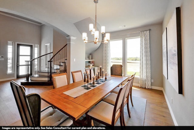 dining space featuring decorative columns, light hardwood / wood-style flooring, and a chandelier