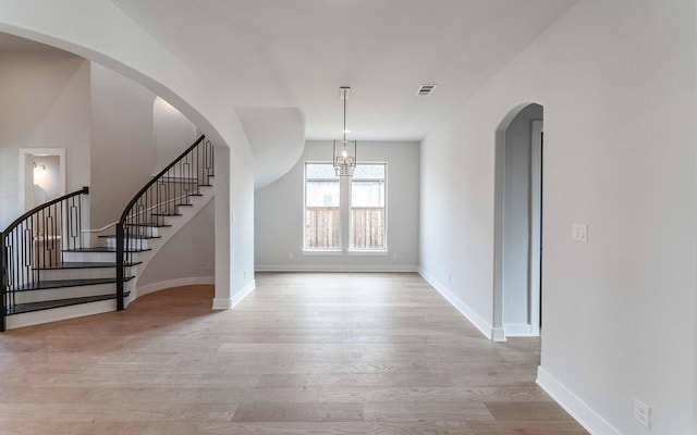 interior space with light wood-style floors, visible vents, stairway, and baseboards