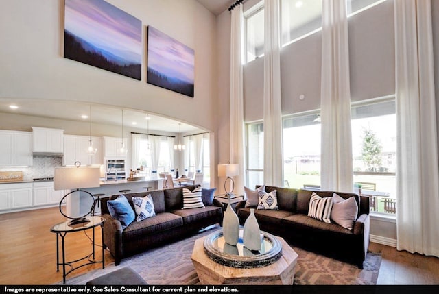 living room featuring a notable chandelier, a towering ceiling, and light hardwood / wood-style flooring