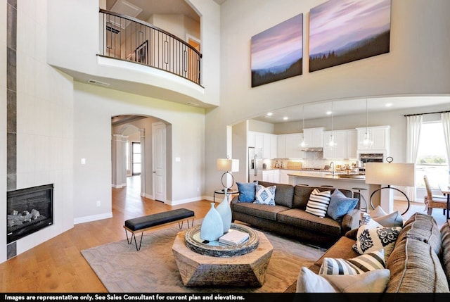 living room featuring a high ceiling, a fireplace, and light wood-type flooring