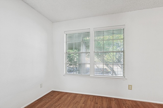 unfurnished room with wood-type flooring and a textured ceiling