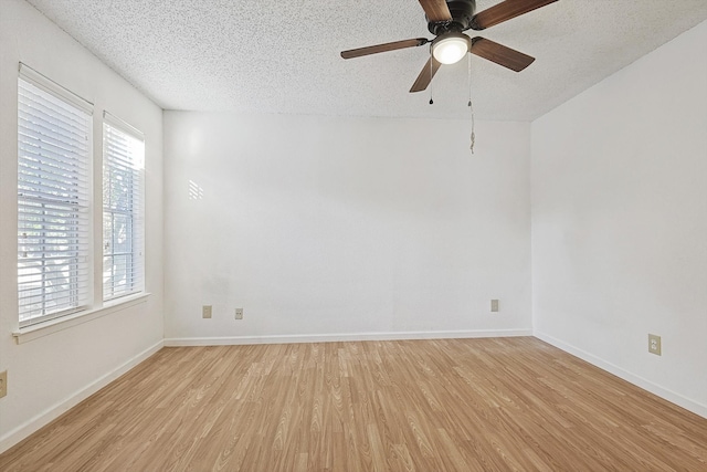 spare room featuring a textured ceiling, light hardwood / wood-style flooring, and a healthy amount of sunlight