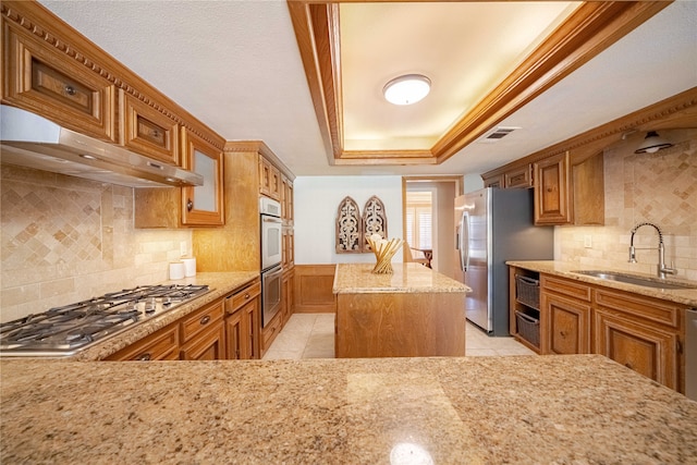 kitchen with extractor fan, stainless steel appliances, backsplash, sink, and a center island