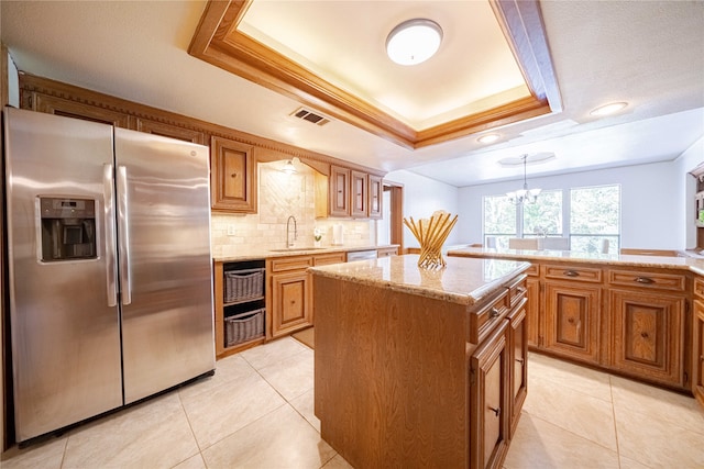 kitchen with a center island, decorative light fixtures, stainless steel appliances, and a raised ceiling