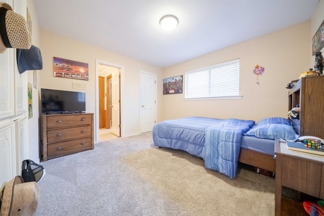 bedroom with connected bathroom and light carpet