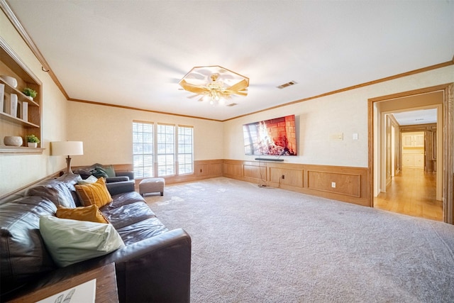 carpeted living room featuring crown molding, built in shelves, and ceiling fan