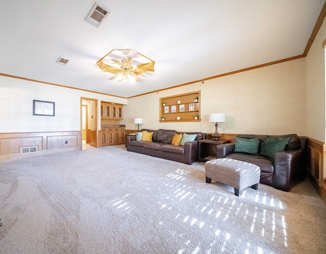 carpeted living room with ceiling fan and ornamental molding