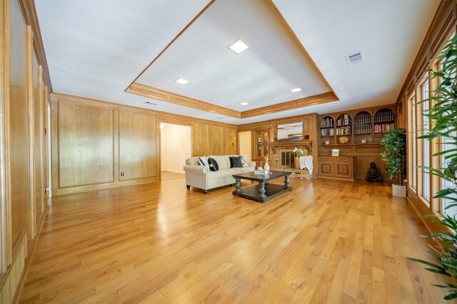 living room featuring a raised ceiling, light hardwood / wood-style flooring, and a fireplace