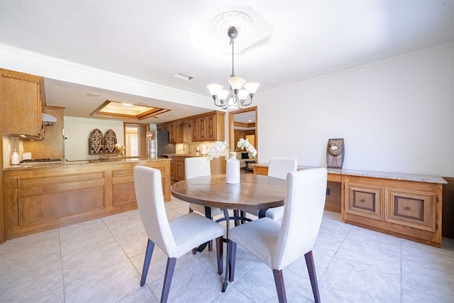 tiled dining area with sink, ornamental molding, and an inviting chandelier