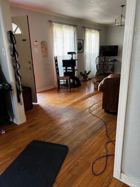 living area featuring crown molding, wood finished floors, and baseboards