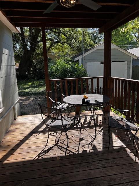 deck featuring a storage shed, outdoor dining area, and an outbuilding