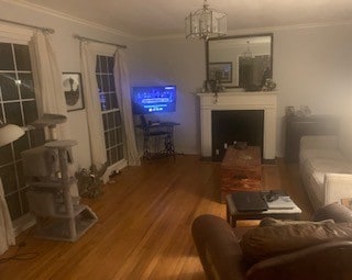 living area featuring a chandelier, wood finished floors, a fireplace, and ornamental molding