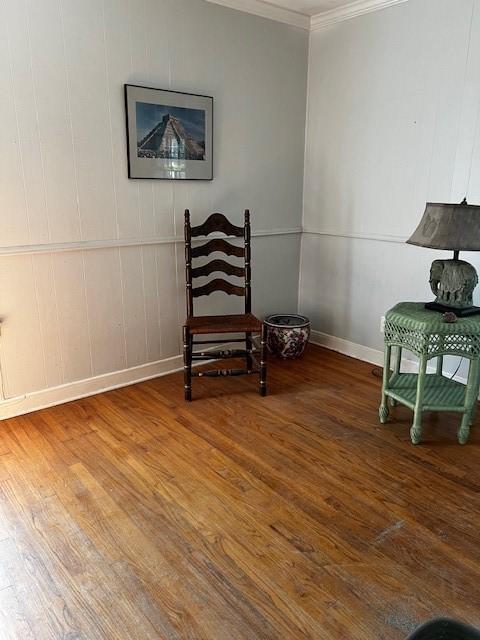 living area with ornamental molding, baseboards, and wood finished floors