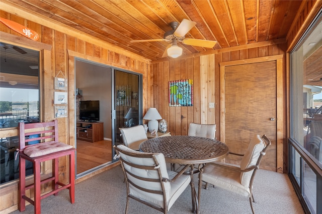 dining area featuring wood walls, ceiling fan, and wooden ceiling