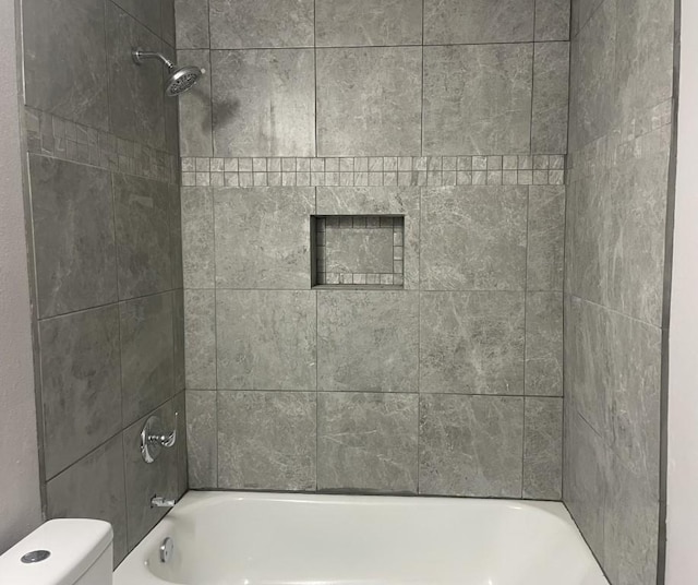 bathroom featuring tiled shower / bath and toilet