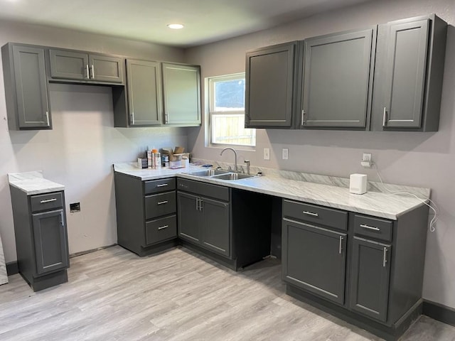 kitchen with gray cabinetry, sink, and light wood-type flooring