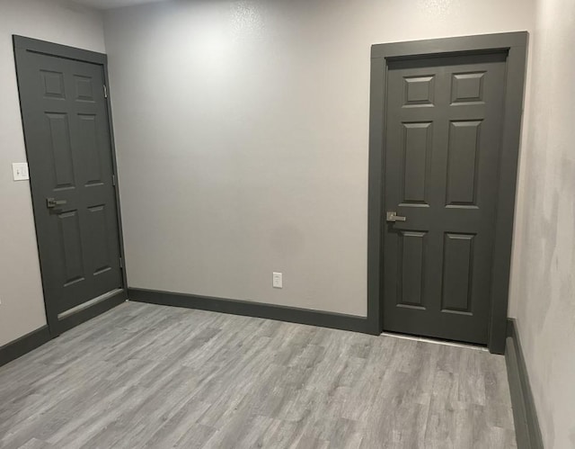 empty room with a baseboard heating unit and light hardwood / wood-style flooring