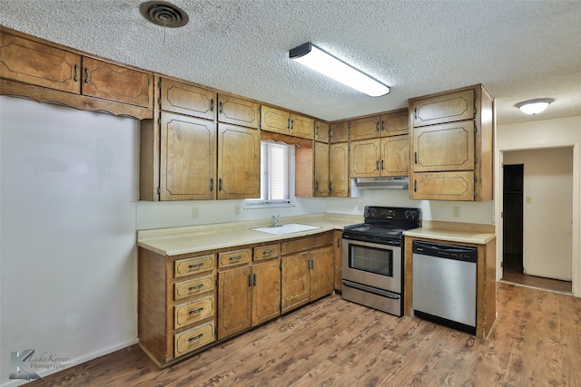 kitchen featuring a textured ceiling, light hardwood / wood-style floors, sink, and stainless steel appliances