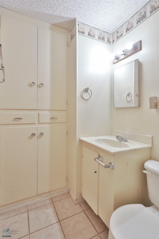 bathroom with tile patterned floors, vanity, a textured ceiling, and toilet