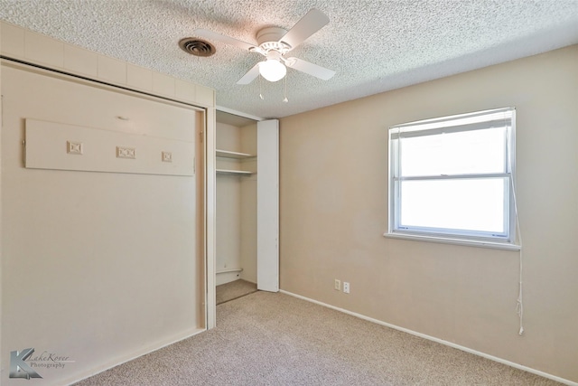 unfurnished bedroom with ceiling fan, a closet, light colored carpet, and a textured ceiling