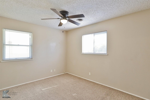 empty room with a textured ceiling, carpet floors, plenty of natural light, and ceiling fan