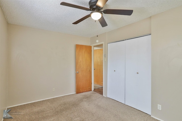 unfurnished bedroom with ceiling fan, a textured ceiling, light carpet, and a closet