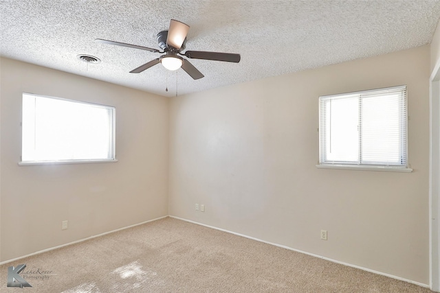 carpeted spare room with a wealth of natural light, ceiling fan, and a textured ceiling