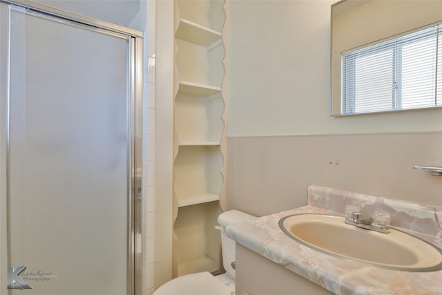 bathroom with vanity, toilet, and a shower with door