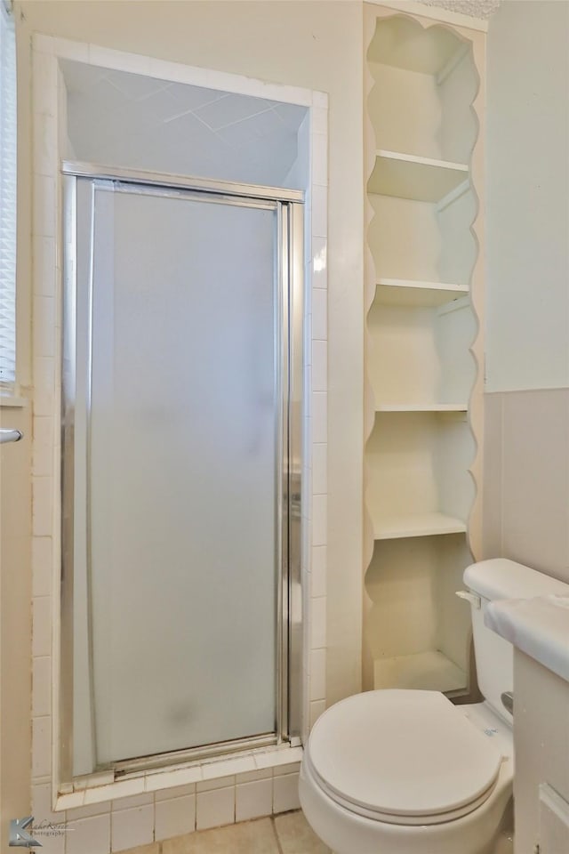 bathroom featuring tile patterned flooring, vanity, a shower with shower door, and toilet