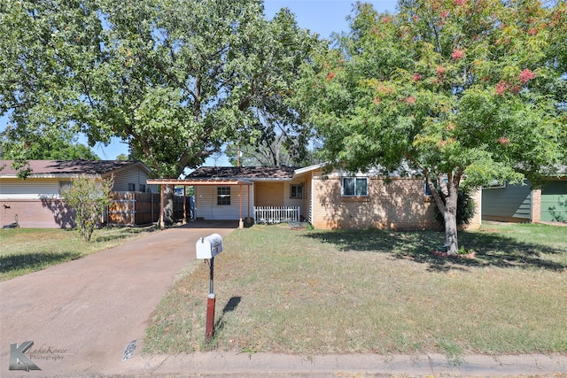 ranch-style home with a front lawn, covered porch, and a carport