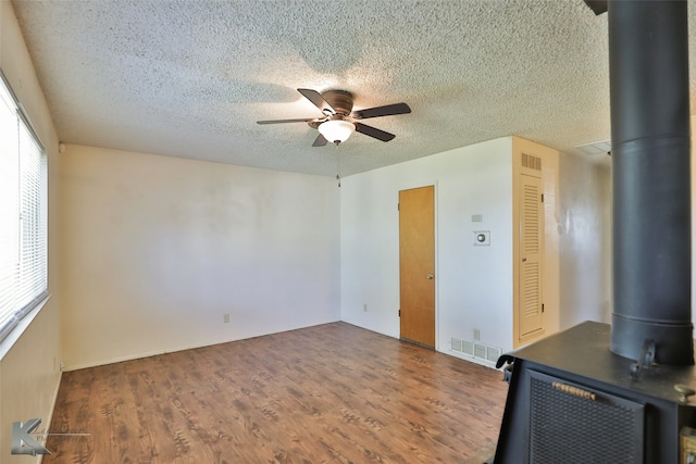 unfurnished room featuring ceiling fan, plenty of natural light, wood-type flooring, and a textured ceiling