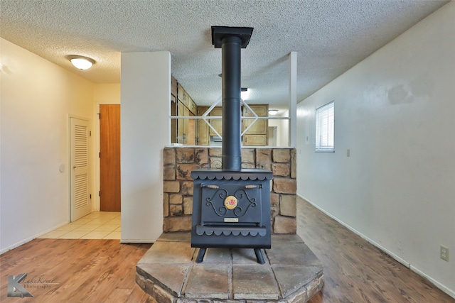 interior details with wood-type flooring, a textured ceiling, and a wood stove