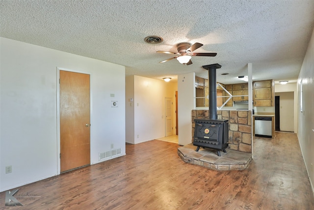 unfurnished living room with hardwood / wood-style floors, ceiling fan, a wood stove, and a textured ceiling