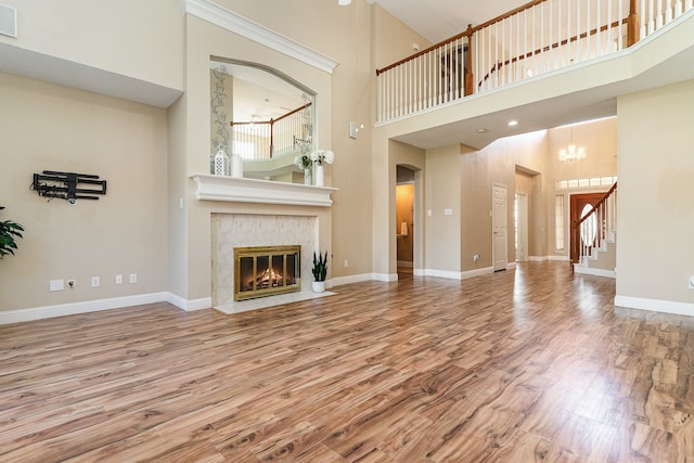 unfurnished living room featuring a fireplace, hardwood / wood-style floors, and a high ceiling