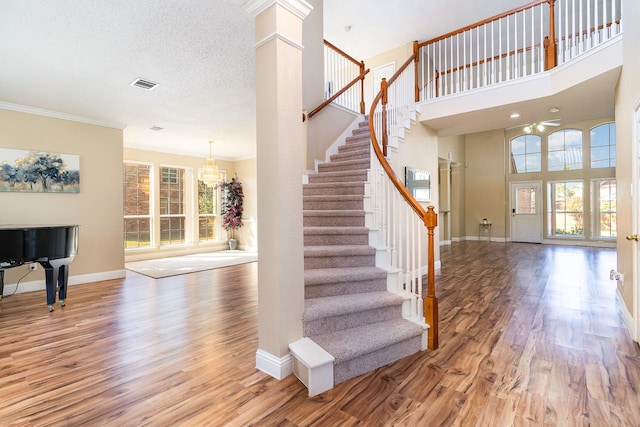 foyer entrance featuring wood-type flooring, a textured ceiling, plenty of natural light, and a high ceiling