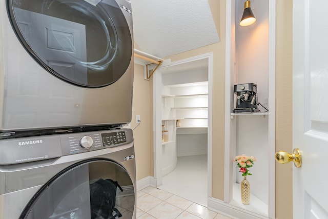 clothes washing area with light tile patterned floors and stacked washer / dryer