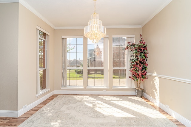 unfurnished dining area with a chandelier, crown molding, and wood-type flooring