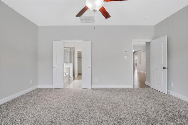 unfurnished bedroom with ceiling fan, ensuite bath, and light colored carpet