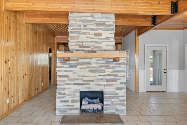 interior details featuring a stone fireplace, wooden walls, wooden ceiling, and beamed ceiling