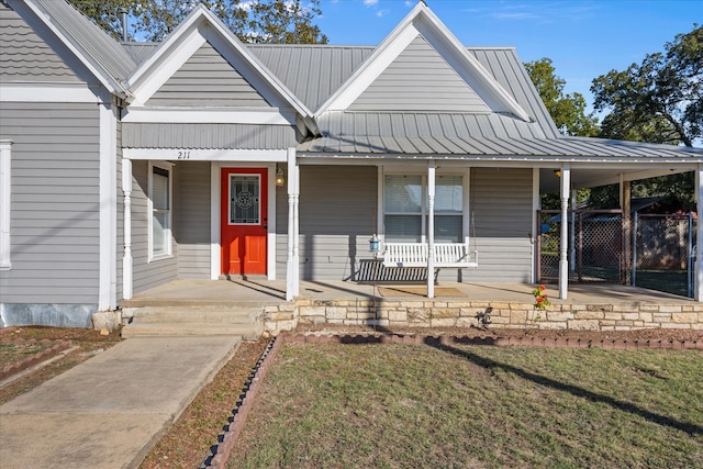 view of front of house featuring covered porch, a front yard, and a carport