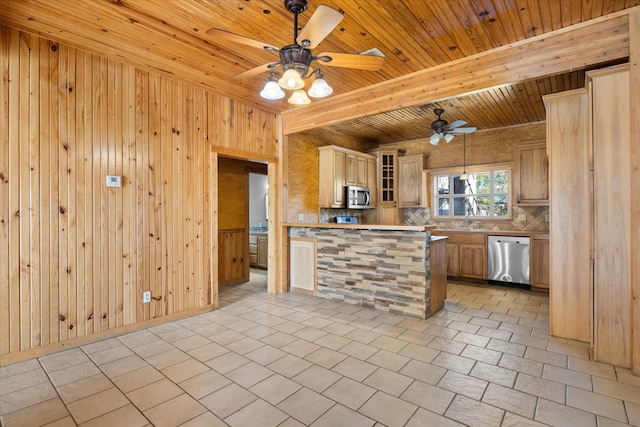 kitchen featuring backsplash, stainless steel appliances, light brown cabinets, and wood walls