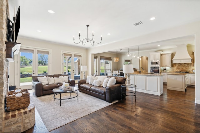 living room with crown molding, french doors, dark hardwood / wood-style floors, and an inviting chandelier