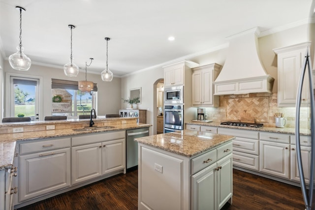 kitchen with sink, stainless steel appliances, dark hardwood / wood-style floors, premium range hood, and a kitchen island