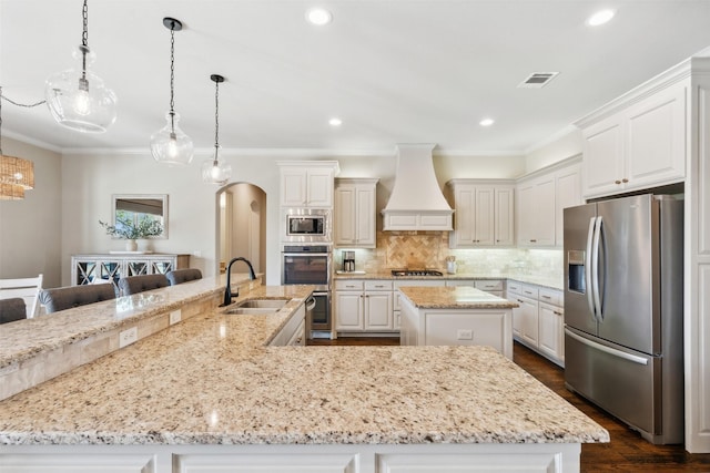 kitchen featuring custom exhaust hood, a spacious island, sink, hanging light fixtures, and stainless steel appliances