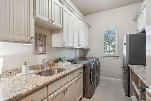 clothes washing area featuring washing machine and clothes dryer, light tile patterned flooring, cabinets, and sink